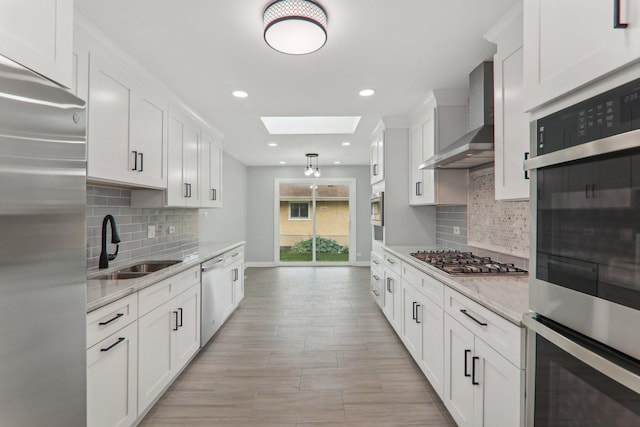 7701 Sawyer Rd, Darien, IL 60561 - kitchen featuring stainless steel appliances, wall chimney range hood, a skylight, white cabinetry, and tasteful backsplash