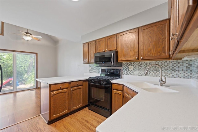 27W414 Melrose Ln, Winfield, IL 60190 - kitchen featuring stainless steel microwave, black range with gas stovetop, a peninsula, light countertops, and tasteful backsplash