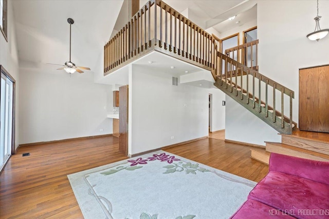 27W414 Melrose Ln, Winfield, IL 60190 - unfurnished living room featuring a high ceiling, wood finished floors, ceiling fan, and stairway