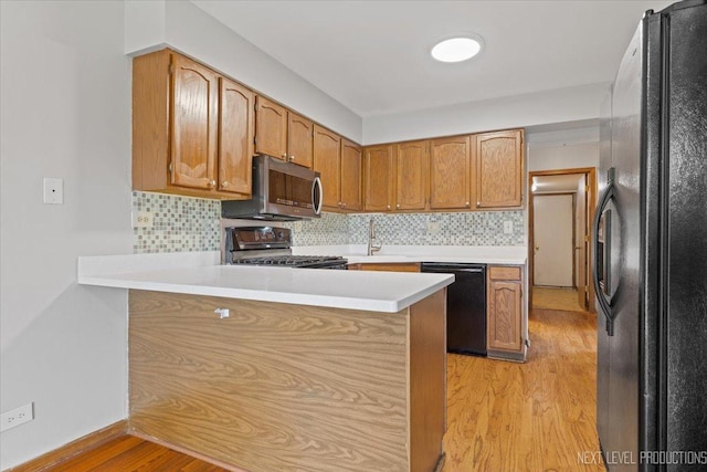 27W414 Melrose Ln, Winfield, IL 60190 - kitchen with black appliances, a peninsula, light wood-style flooring, light countertops, and decorative backsplash