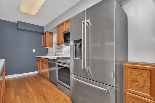 25034 S Center St, Channahon, IL 60410 - kitchen featuring appliances with stainless steel finishes, brown cabinetry, light wood-type flooring, and light countertops