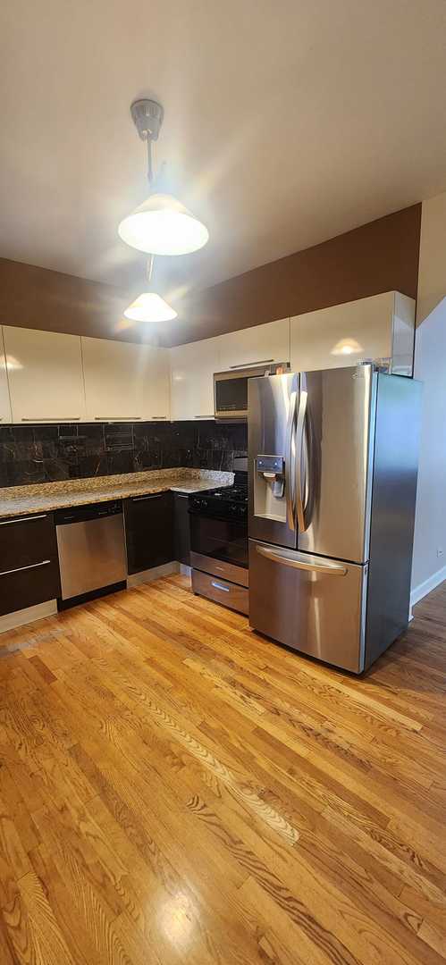 3700 W Cermak Rd Unit 1, Chicago, IL 60623 - kitchen with appliances with stainless steel finishes, light wood-type flooring, tasteful backsplash, and white cabinetry