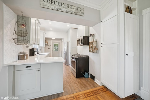 241 Hoy Ave, Woodstock, IL 60098 - kitchen with appliances with stainless steel finishes, light countertops, white cabinetry, light wood-style floors, and a peninsula