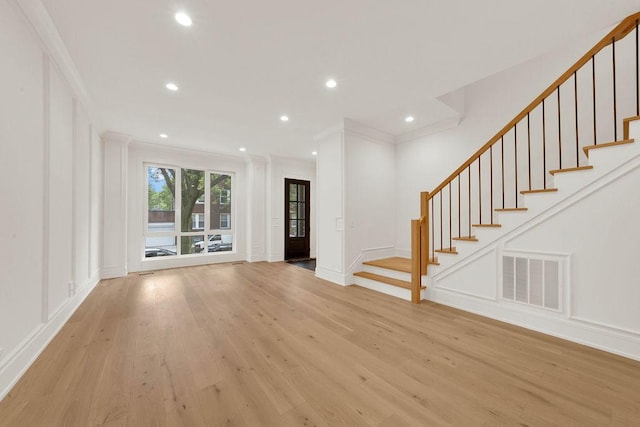 2248 W Ainslie St, Chicago, IL 60625 - unfurnished living room with crown molding, light wood-style flooring, a decorative wall, recessed lighting, and stairway