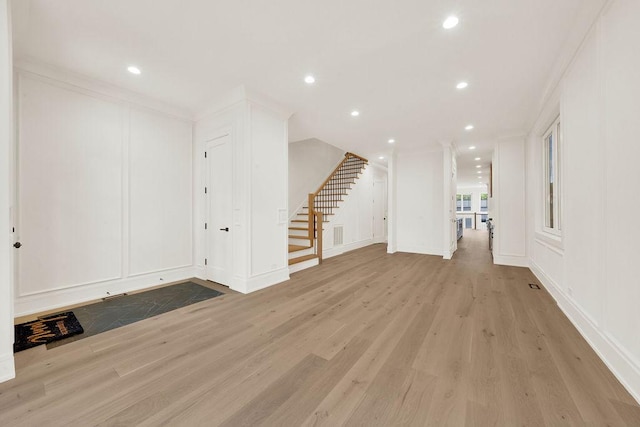 2248 W Ainslie St, Chicago, IL 60625 - unfurnished living room featuring stairway, light wood-style floors, crown molding, recessed lighting, and a decorative wall