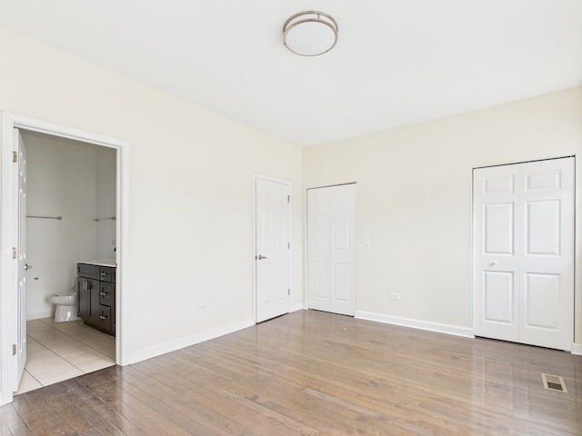 738 S Kedzie Ave Unit 3, Chicago, IL 60612 - unfurnished bedroom with wood finished floors, multiple closets, and ensuite bath