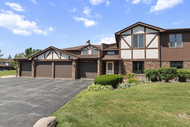 12912 Mill Dr E, Palos Park, IL 60464 - tudor house with brick siding, driveway, a front lawn, and a garage