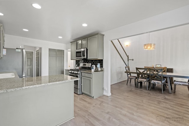 516 Madison Ln, Elgin, IL 60123 - kitchen featuring appliances with stainless steel finishes, gray cabinetry, light wood-type flooring, light stone counters, and a chandelier