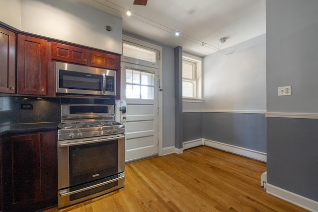 6712 N Maplewood Ave, Chicago, IL 60645 - kitchen with appliances with stainless steel finishes, baseboard heating, dark brown cabinets, light wood-style flooring, and dark countertops