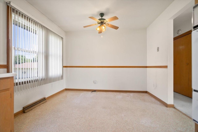 200 S Madison St, Towanda, IL 61776 - empty room featuring a ceiling fan, light colored carpet, and a baseboard heating unit