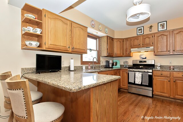 3406 W Bretons Dr, Mchenry, IL 60050 - kitchen featuring stainless steel range with gas cooktop, under cabinet range hood, a peninsula, light stone counters, and a breakfast bar