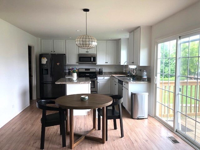 900 Heartland Park Ln, Antioch, IL 60002 - kitchen with stainless steel appliances, light wood finished floors, hanging light fixtures, a center island, and light stone countertops