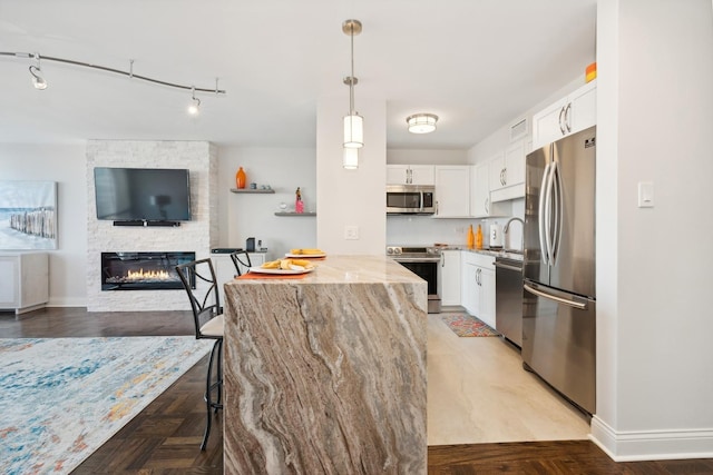 601 E 32nd St Unit 1002, Chicago, IL 60616 - kitchen with appliances with stainless steel finishes, light stone countertops, white cabinets, decorative light fixtures, and a stone fireplace