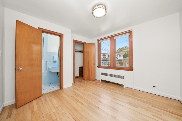 3901 N Neva Ave, Chicago, IL 60634 - unfurnished bedroom featuring radiator, light wood finished floors, and ensuite bathroom