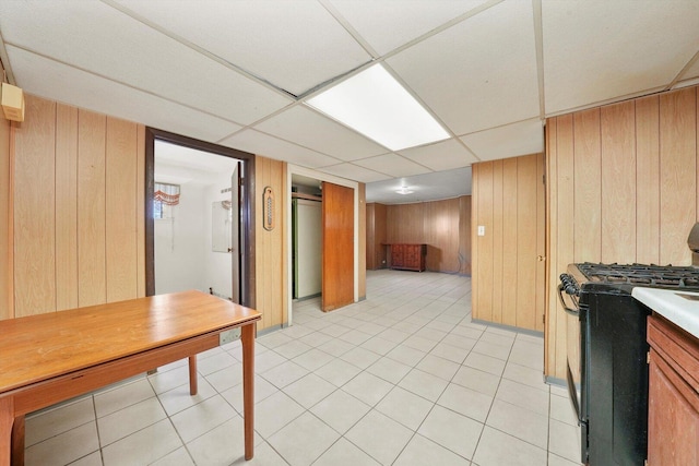 3901 N Neva Ave, Chicago, IL 60634 - kitchen featuring black range with gas cooktop, wood walls, light tile patterned flooring, and a drop ceiling
