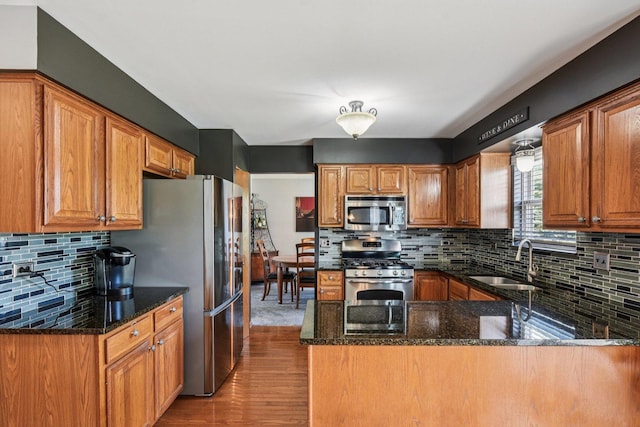 5509 Hickory Grove Ct, Plainfield, IL 60586 - kitchen with appliances with stainless steel finishes, light wood-style floors, a peninsula, backsplash, and dark stone counters