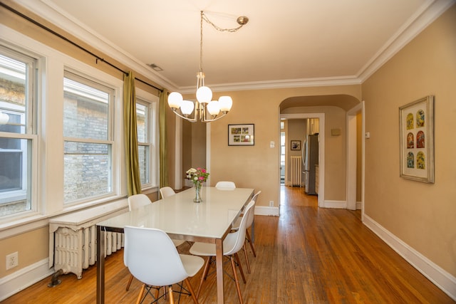 2815 W Fitch Ave, Chicago, IL 60645 - dining room with arched walkways, radiator, a chandelier, dark wood-style floors, and ornamental molding