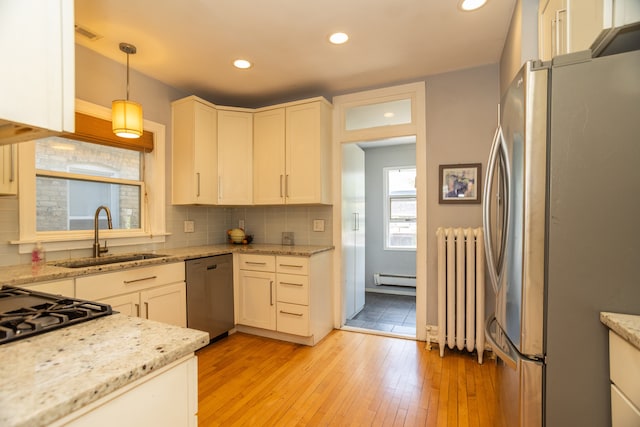 2815 W Fitch Ave, Chicago, IL 60645 - kitchen with appliances with stainless steel finishes, radiator, a baseboard heating unit, light wood-type flooring, and decorative backsplash