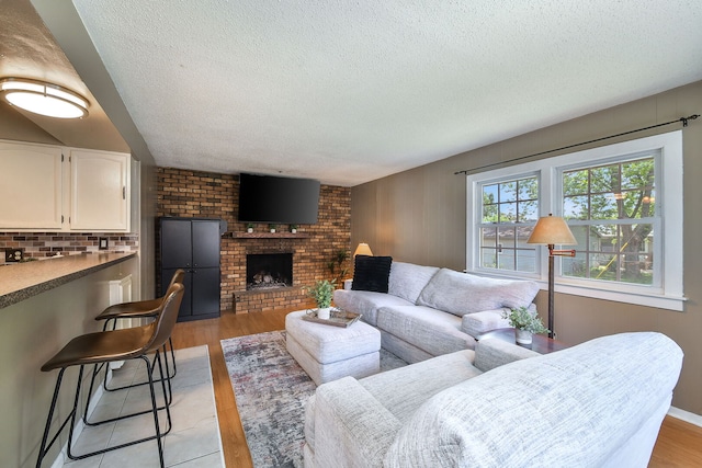 1747 Pleasant Ave, Saint Charles, IL 60174 - living room featuring a textured ceiling, light wood finished floors, and a brick fireplace