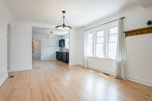 1833 Cuyler Ave, Berwyn, IL 60402 - unfurnished living room featuring light wood-style flooring, arched walkways, and a chandelier