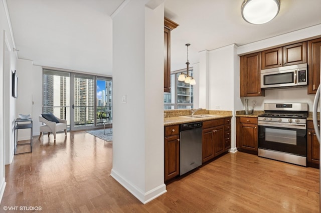 420 E Waterside Dr Unit 1103, Chicago, IL 60601 - kitchen with stainless steel appliances, light wood finished floors, hanging light fixtures, light stone countertops, and brown cabinets