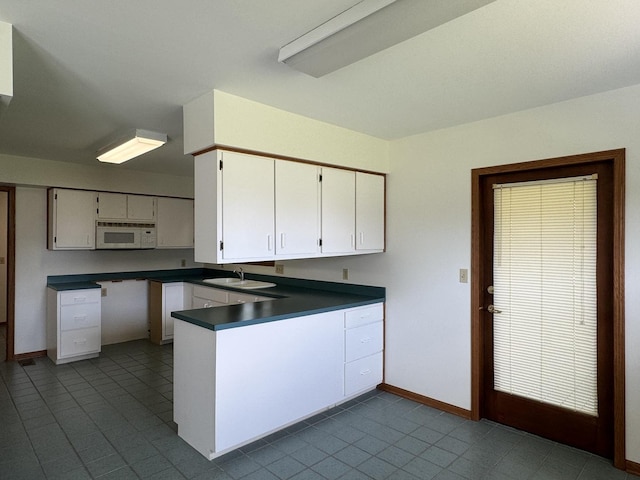 532 E 2nd St, Herscher, IL 60941 - kitchen with white microwave, a peninsula, dark countertops, white cabinets, and tile patterned floors