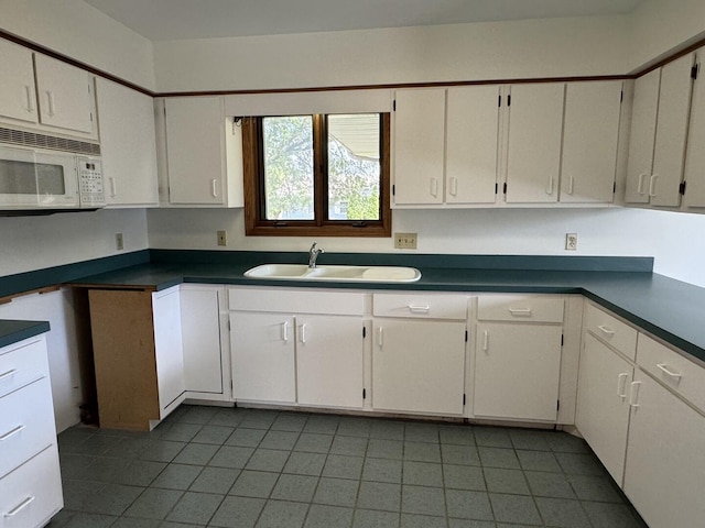 532 E 2nd St, Herscher, IL 60941 - kitchen with white microwave, tile patterned flooring, dark countertops, and white cabinetry
