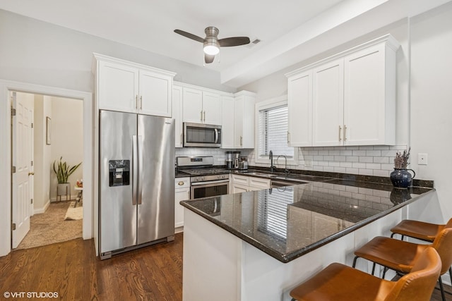 2930 N Damen Ave Unit 2, Chicago, IL 60618 - kitchen featuring appliances with stainless steel finishes, dark wood finished floors, a peninsula, and white cabinets