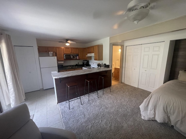 45 Nassau Colony Unit 4, Fox Lake, IL 60020 - kitchen featuring white appliances, a ceiling fan, a peninsula, a breakfast bar, and brown cabinetry