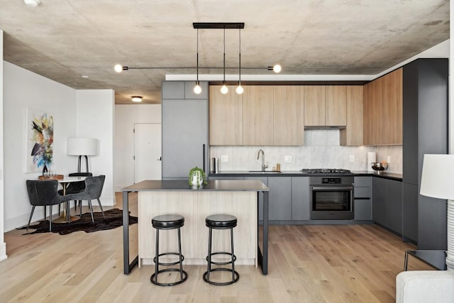 234 W Polk St Unit 3403, Chicago, IL 60607 - kitchen featuring appliances with stainless steel finishes, dark countertops, light wood-type flooring, a breakfast bar area, and a center island