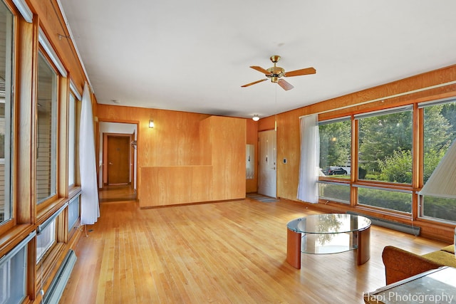 34719 N Nokomis Trl, Mchenry, IL 60051 - unfurnished living room with light wood-style floors, ceiling fan, plenty of natural light, wooden walls, and a baseboard radiator