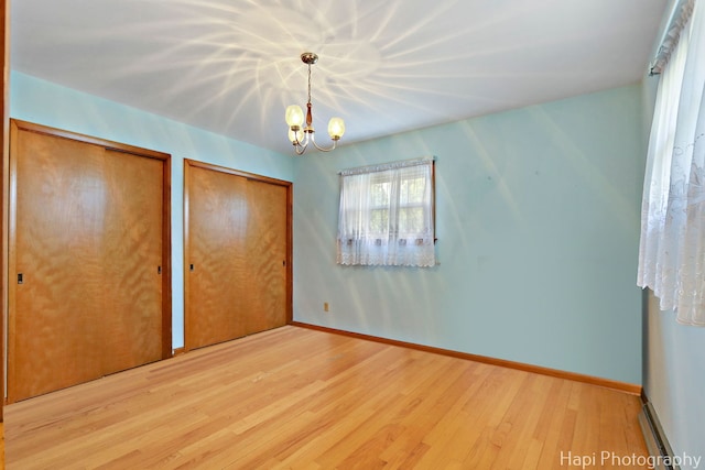 34719 N Nokomis Trl, Mchenry, IL 60051 - unfurnished bedroom with multiple closets, wood finished floors, and a chandelier