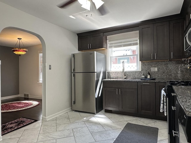 652 Beckman Dr, Kankakee, IL 60901 - kitchen featuring freestanding refrigerator, dark stone countertops, a ceiling fan, black stove, and arched walkways
