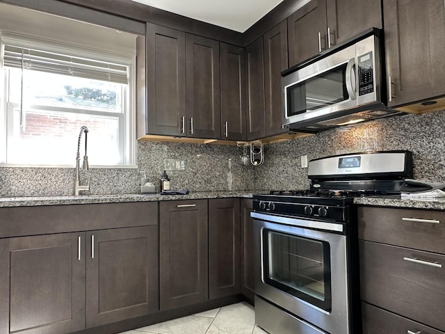 652 Beckman Dr, Kankakee, IL 60901 - kitchen featuring stainless steel appliances, stone counters, dark brown cabinetry, and tasteful backsplash