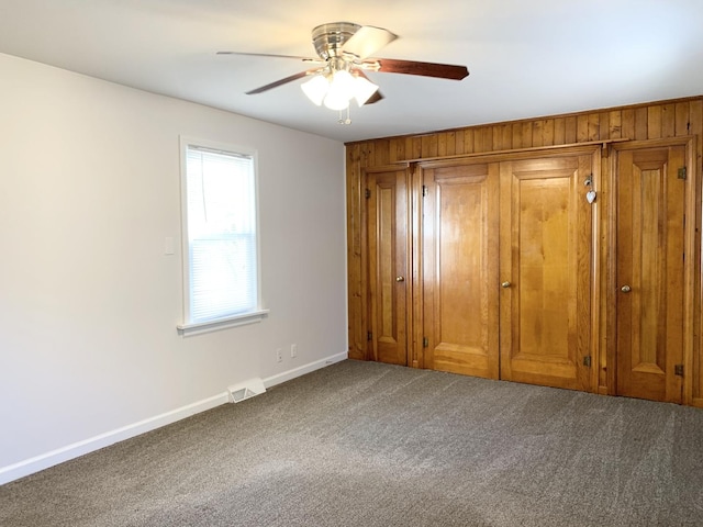 652 Beckman Dr, Kankakee, IL 60901 - unfurnished bedroom with carpet, wooden walls, a closet, and a ceiling fan