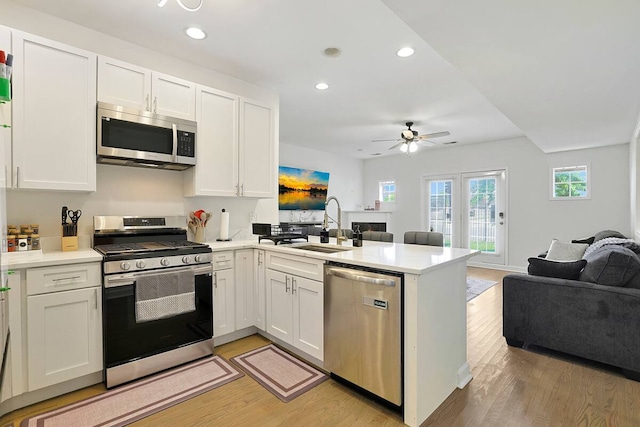 2355 W Congress Pkwy Unit 1, Chicago, IL 60612 - kitchen with stainless steel appliances, open floor plan, light wood-style flooring, a peninsula, and ceiling fan