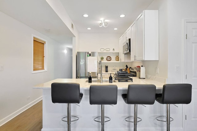 2355 W Congress Pkwy Unit 1, Chicago, IL 60612 - kitchen featuring appliances with stainless steel finishes, a peninsula, a kitchen breakfast bar, white cabinets, and recessed lighting