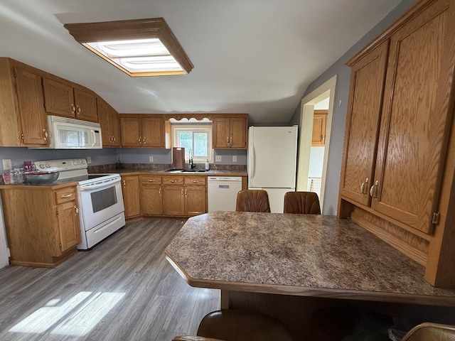 310 E Chippewa St, Dwight, IL 60420 - kitchen with white appliances, vaulted ceiling, wood finished floors, brown cabinets, and dark countertops