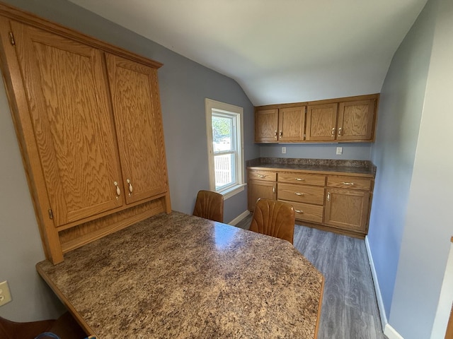 310 E Chippewa St, Dwight, IL 60420 - kitchen with wood finished floors, vaulted ceiling, brown cabinetry, dark countertops, and a peninsula
