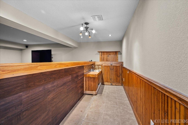 317 Plymouth Ct, Sycamore, IL 60178 - indoor wet bar with wainscoting, wooden walls, a textured ceiling, and light tile patterned floors