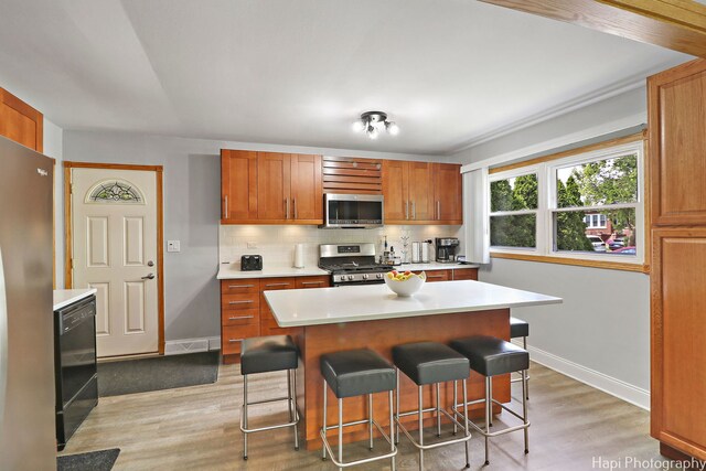 1569 Sherman Pl, Des Plaines, IL 60016 - kitchen featuring stainless steel appliances, light countertops, light wood-type flooring, and a kitchen breakfast bar