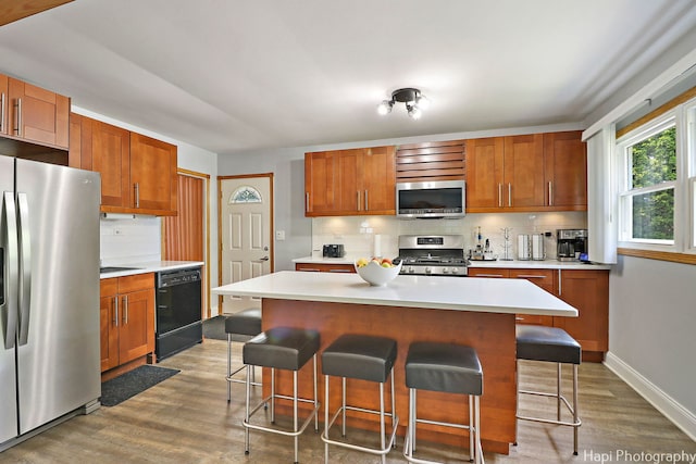 1569 Sherman Pl, Des Plaines, IL 60016 - kitchen featuring stainless steel appliances, backsplash, wood finished floors, and a kitchen breakfast bar