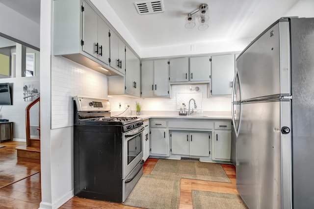 733 Ashland Ave, Chicago Heights, IL 60411 - kitchen featuring stainless steel appliances, light wood-style flooring, decorative backsplash, and light countertops