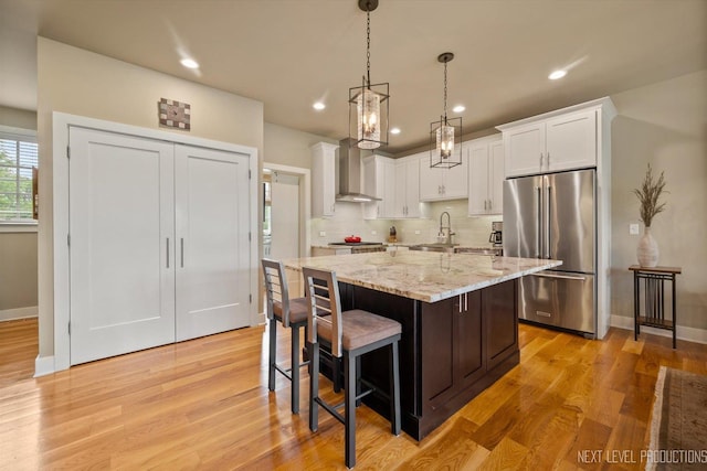 520 Ohio Ave, Saint Charles, IL 60174 - kitchen featuring appliances with stainless steel finishes, wall chimney exhaust hood, white cabinets, decorative backsplash, and light wood-type flooring