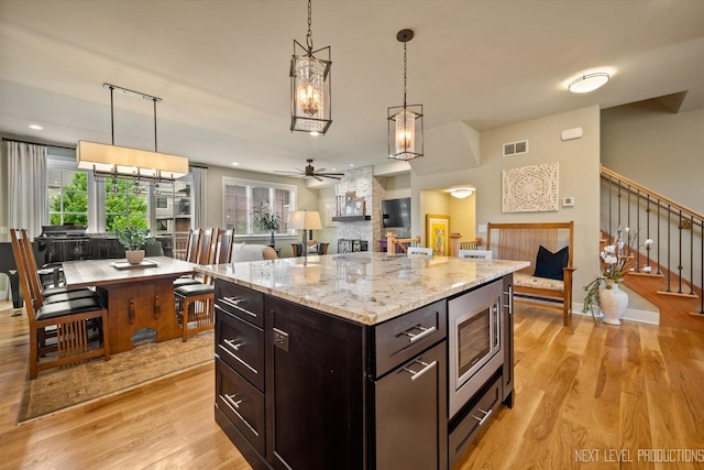 520 Ohio Ave, Saint Charles, IL 60174 - kitchen with a fireplace, a ceiling fan, light wood-style flooring, stainless steel microwave, and pendant lighting