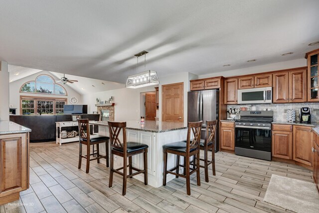 1245 Patriot Way, Bourbonnais, IL 60914 - kitchen with stainless steel appliances, open floor plan, a ceiling fan, brown cabinetry, and a breakfast bar