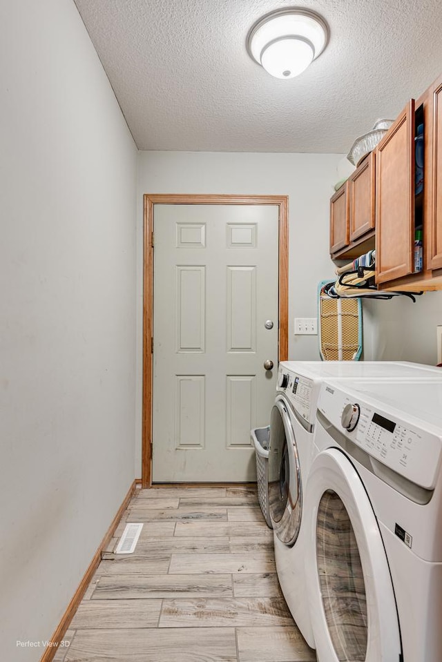1245 Patriot Way, Bourbonnais, IL 60914 - laundry room featuring cabinet space, washing machine and dryer, a textured ceiling, and light wood-style flooring