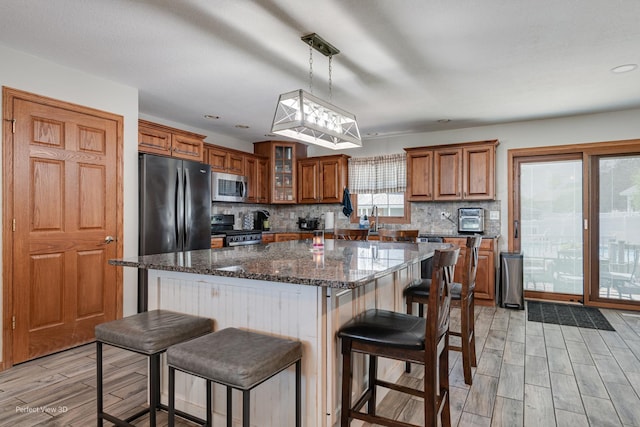 1245 Patriot Way, Bourbonnais, IL 60914 - kitchen featuring stainless steel appliances, brown cabinets, light wood-type flooring, a breakfast bar, and backsplash