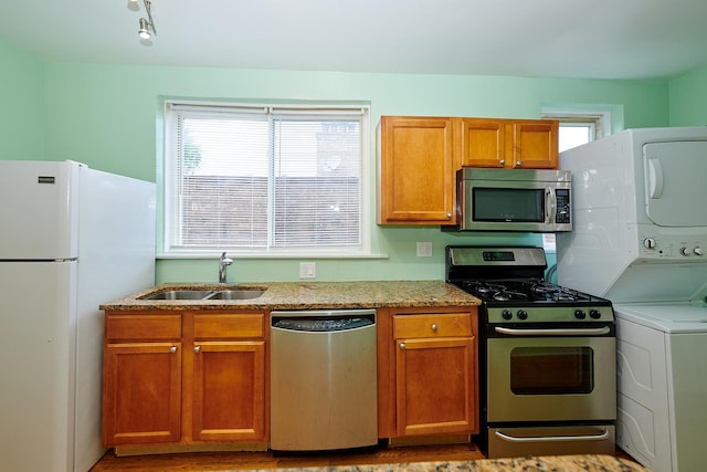 6333 N Francisco Ave Unit 2, Chicago, IL 60659 - kitchen featuring stainless steel appliances, stacked washer / dryer, brown cabinets, and light stone countertops