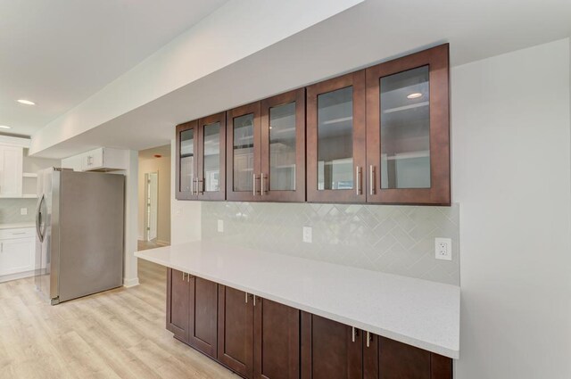 1927 Lakewood Dr, Wilmington, IL 60481 - kitchen with freestanding refrigerator, light wood-style floors, light countertops, decorative backsplash, and glass insert cabinets